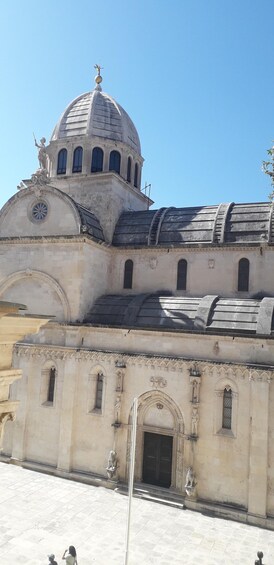 A historic building with a dome, arched windows, and statues. 1