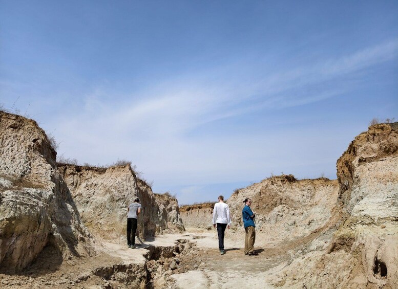 Three people walking on a rocky path between cliffs. 4