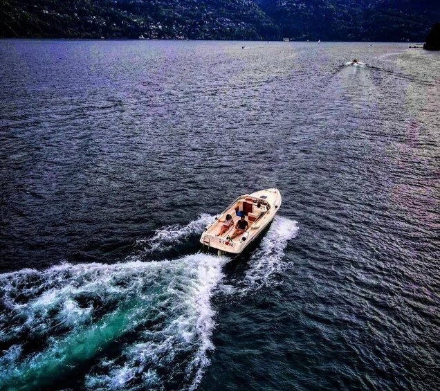 Un velero en un lago con estela, rodeado de aguas tranquilas y montañas al fondo. 2