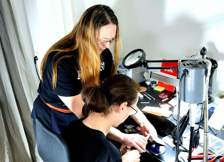 A person working on a mechanical device with tools and a magnifying lamp. 1