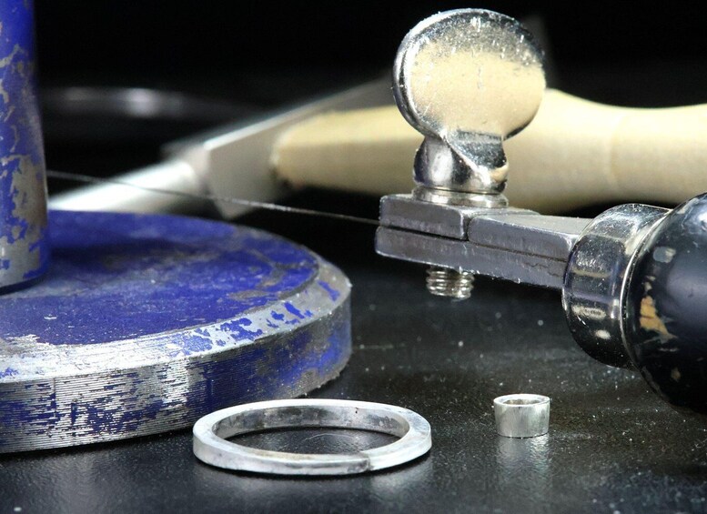 A metal ring, a small cylindrical object, and a tool with a handle on a dark surface. 5