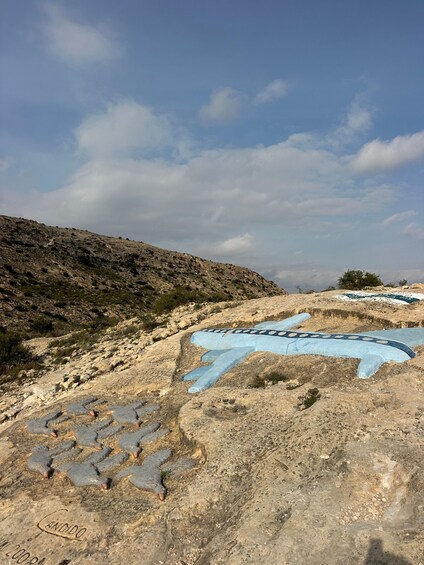 A rocky landscape with a blue-painted airplane and a bird sculpture. 2
