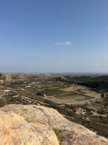 A mountainous landscape with a clear sky, rocky outcrops, and scattered buildings. 5