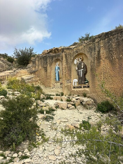A rock wall with religious murals, including figures of saints and inscriptions. 1