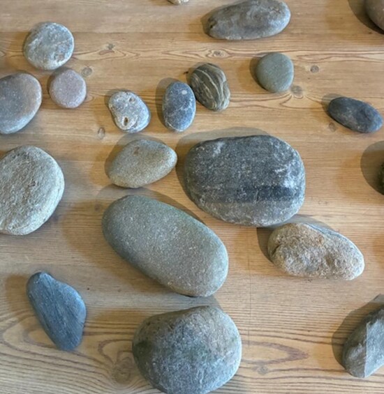 A collection of smooth, rounded stones of various sizes and colors scattered on a wooden surface. 4