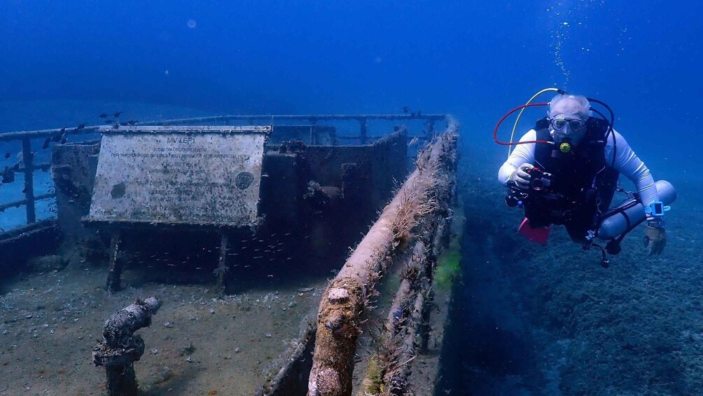 A diver exploring an underwater wreck with a signboard. 3
