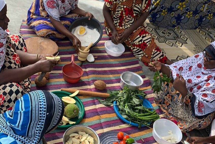 A group of women sitting on a striped mat, preparing food with various ingredients and utensils. 5