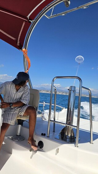 A person on a boat with a clear blue sky and a coastline in the background. 5
