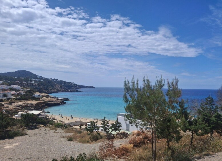 A coastal landscape with a beach, clear blue sea, and a mountainous backdrop. 4