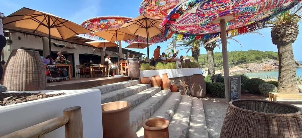 Outdoor seating with umbrellas, terracotta pots, and a coastal view. 5