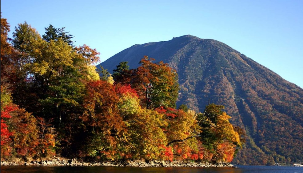 Une montagne aux couleurs automnales, un ciel dégagé et une étendue d’eau calme. 5