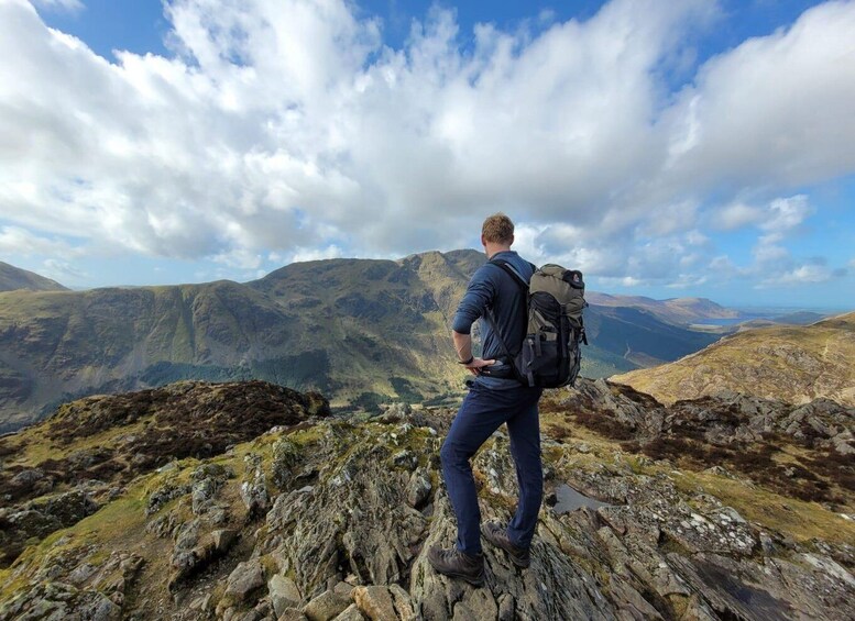 A hiker standing on a rocky outcrop with a mountainous landscape in the background. 3