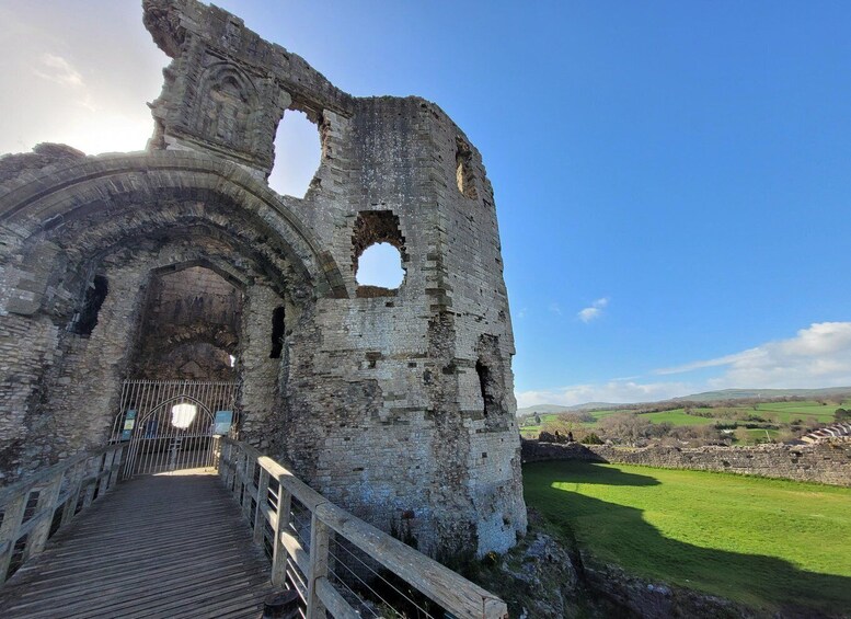 A historic stone archway leading into a ruin with a wooden walkway. 4