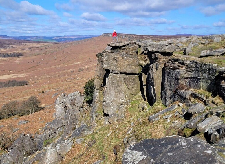 A person standing on a rock formation with a vast landscape in the background. 5
