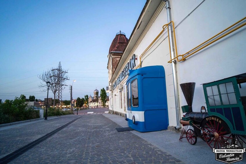 A cobblestone street with a blue tram and a vintage steam engine. 5