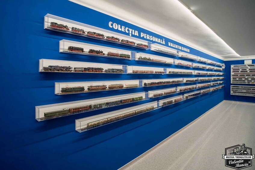 A museum wall with multiple train models displayed in glass cases. 2