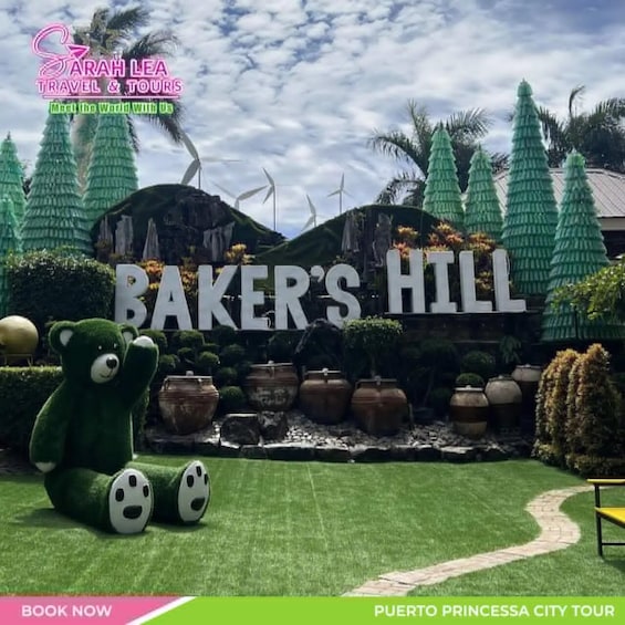 A sign for 'Baker's Hill' with a green bear statue, potted plants, and wind turbines in the background. 1