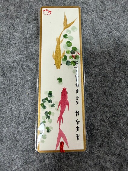 A traditional painting with gold and red fish, green leaves, and Chinese characters. 1