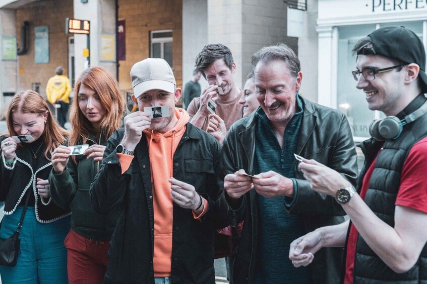 A group of people standing on a street, some holding smartphones. 4