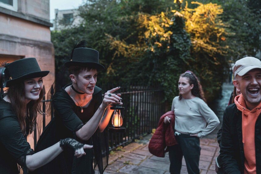 A group of people walking outdoors at dusk, with one person holding a lantern. 1