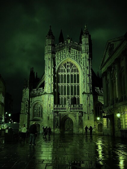 A Gothic-style cathedral with a large arched window and two towers, illuminated at night. 5