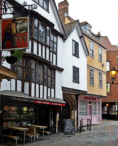 A traditional street with a pub named 'Bobby's Fish Bar' and a shop called 'Central Rose.' 1