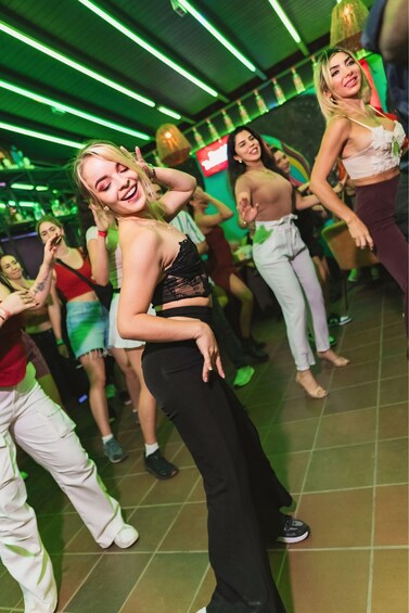 A group of people dancing in a dimly lit room with green lighting. 4