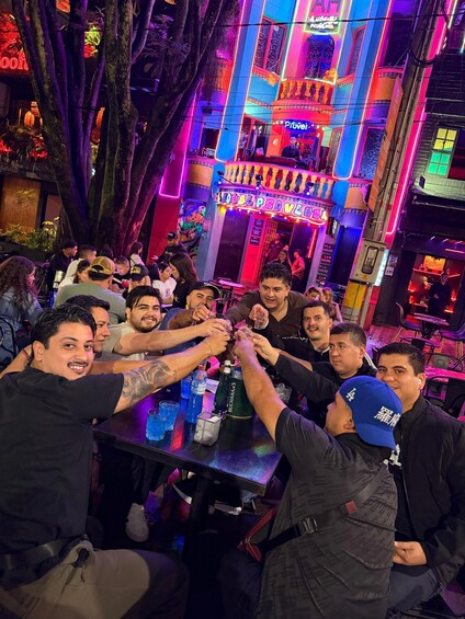 A group of people toasting at a bar with neon lights and a sign that reads 'PROVEN HOUSE.' 2
