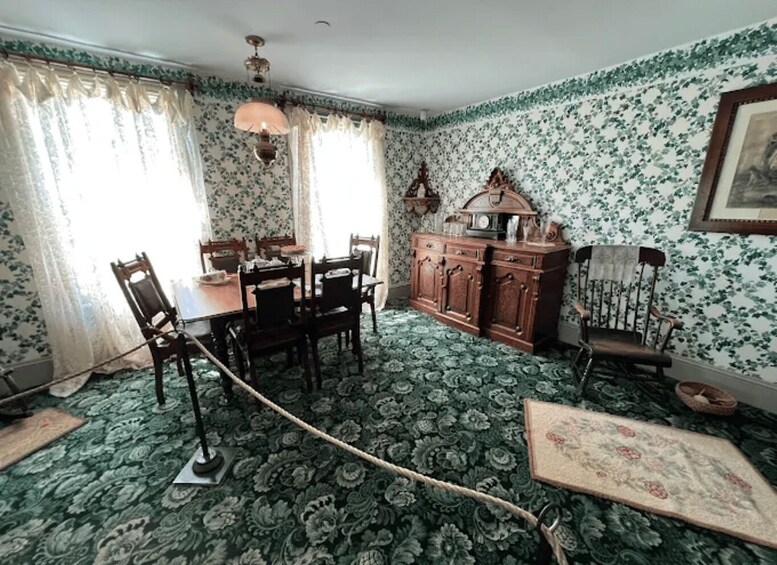 A room with a dining table, chairs, a wooden cabinet, and patterned wallpaper. 4