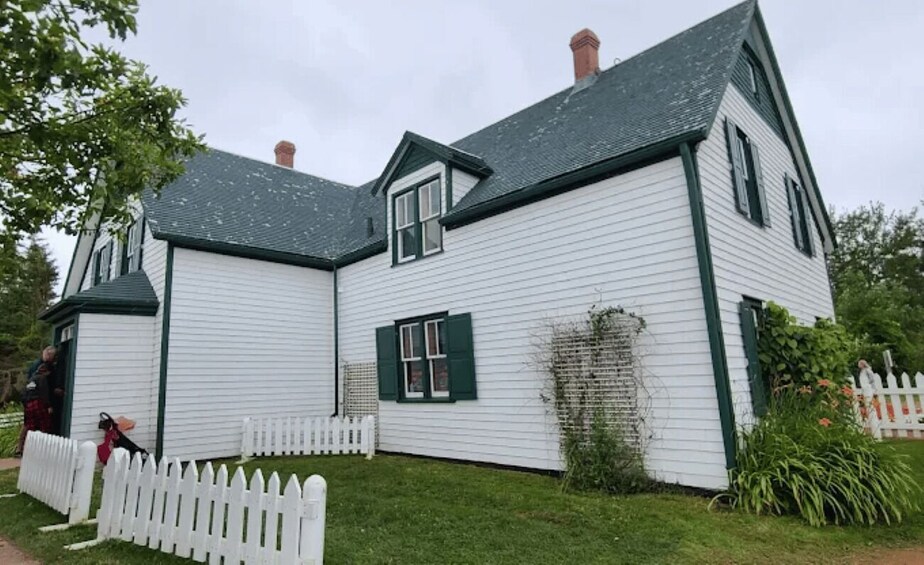 A white house with green shutters and a white picket fence. 5