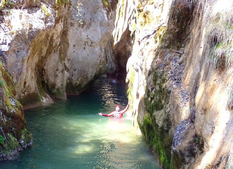 A kayaker in a narrow canyon with clear water and rocky walls. 3