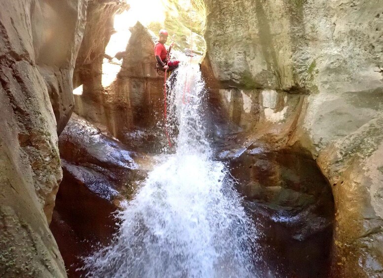 A person rappelling down a waterfall in a rocky canyon. 2