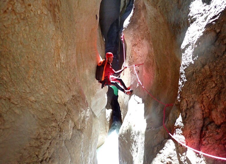 A person rappelling down a rocky canyon wall. 5
