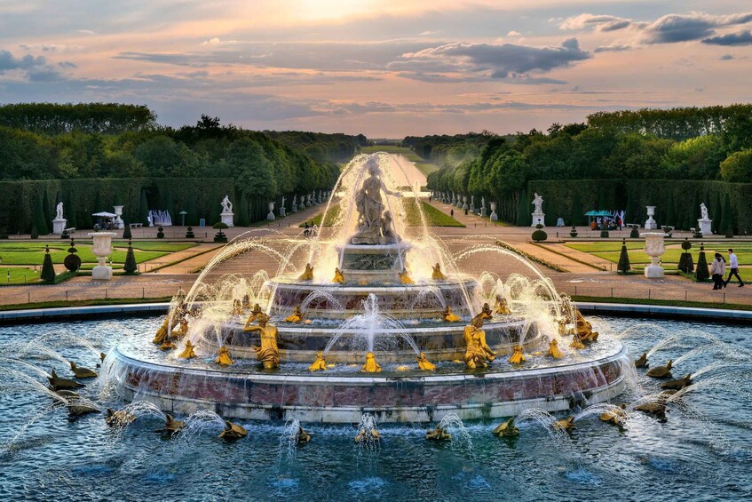 A grand fountain with multiple tiers and statues, surrounded by neatly trimmed hedges and a formal garden layout. 5