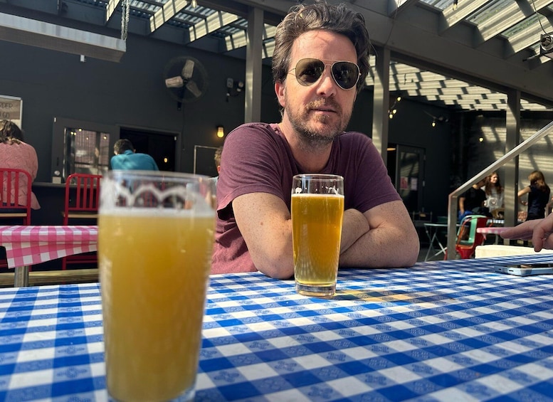 A person sitting at a table with a glass of beer and a checkered tablecloth. 1