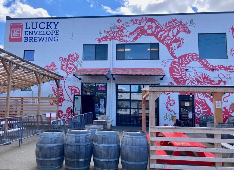 A building with a red dragon mural, wooden barrels, and a sign reading 'Lucky Envelope Brewing.' 4