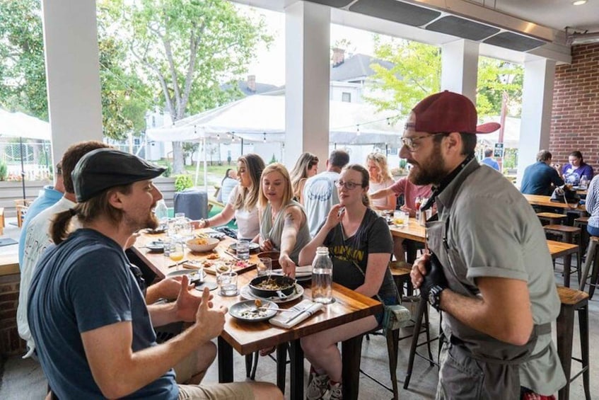 A group of people dining at an outdoor restaurant with tables and chairs. 5