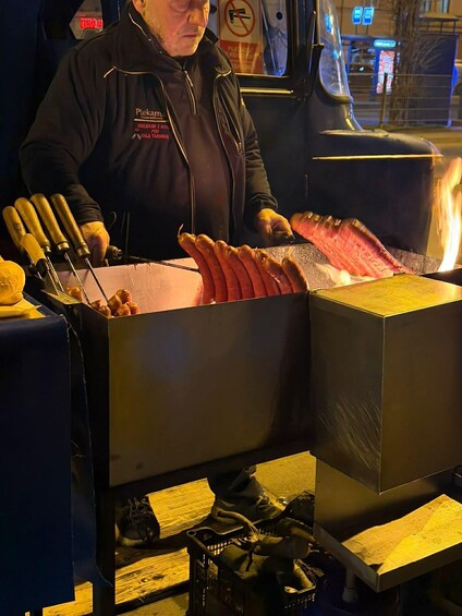 A person grilling sausages on a portable grill at night. 5