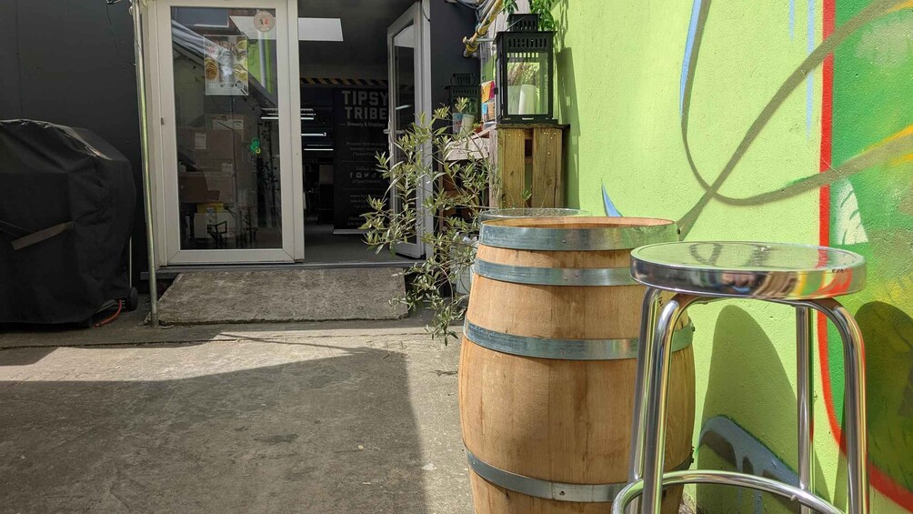 A wooden barrel, a metal stool, and a building entrance with a glass door. 5