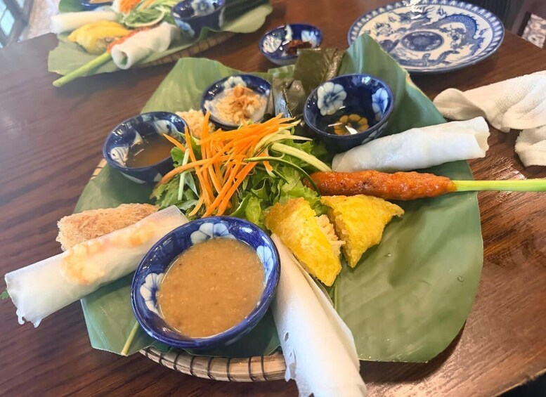 A plate of Vietnamese cuisine with spring rolls, fresh herbs, and dipping sauces. 5