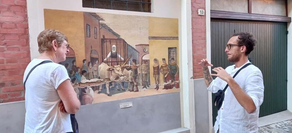 A mural on a building wall depicting a historical scene with people and animals. 3