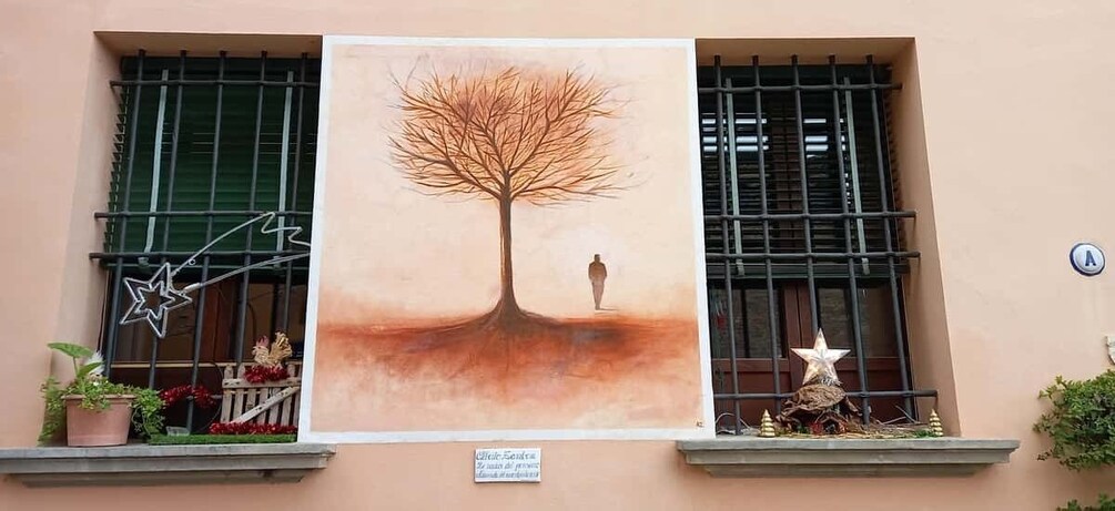 A building facade with a large mural of a tree and a person, potted plants, and a star decoration. 2