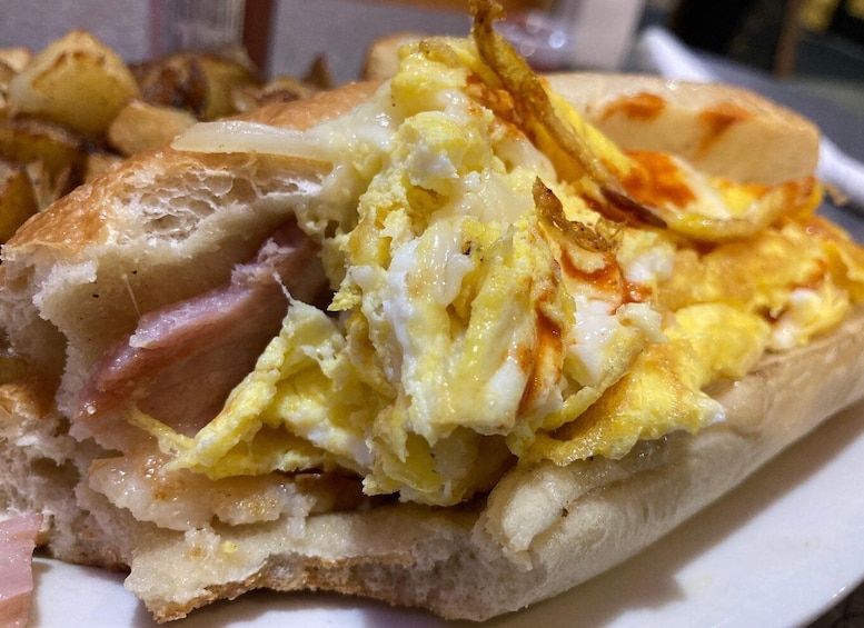 A sandwich with eggs and ham on a white plate. 1