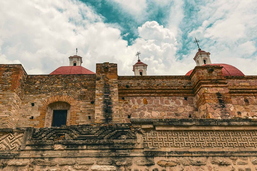 A historic stone building with red domes and a weather vane. 3