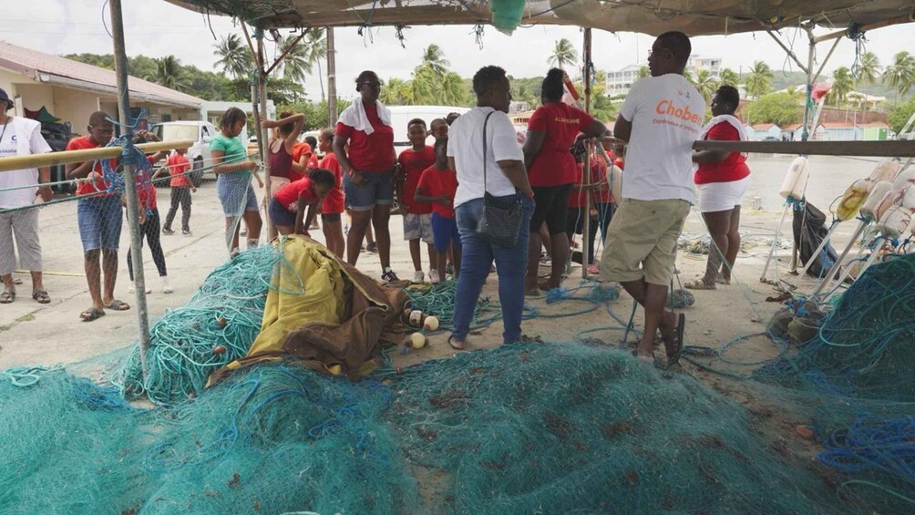 A group of people gathered around fishing nets and equipment under a shelter. 4