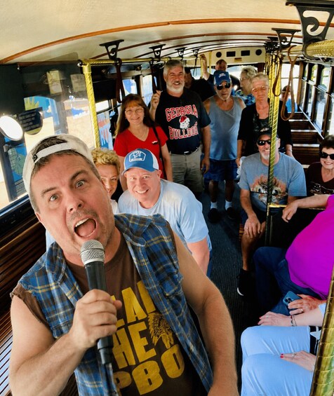 A group of people on a bus with a man holding a microphone. 2