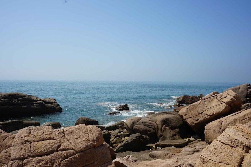 A rocky coastline with large boulders and the ocean. 4