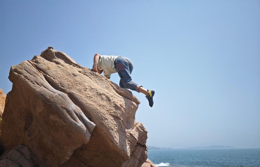 A person rock climbing on a large rock formation by the sea. 1
