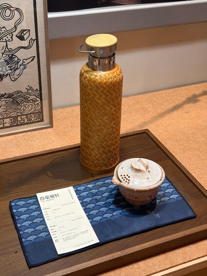 A wooden tray with a ceramic cup and a woven water bottle. 3