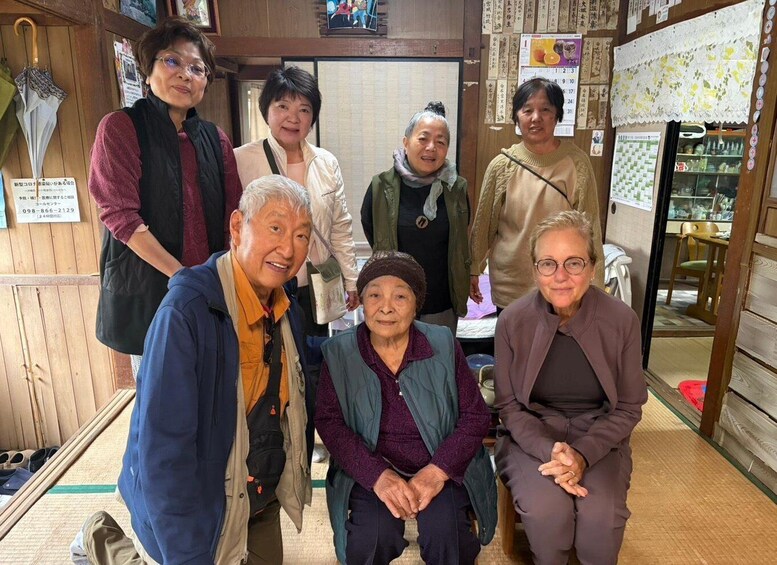 A group of people in a traditional Japanese setting with wooden interiors and a visible menu on the wall. 1